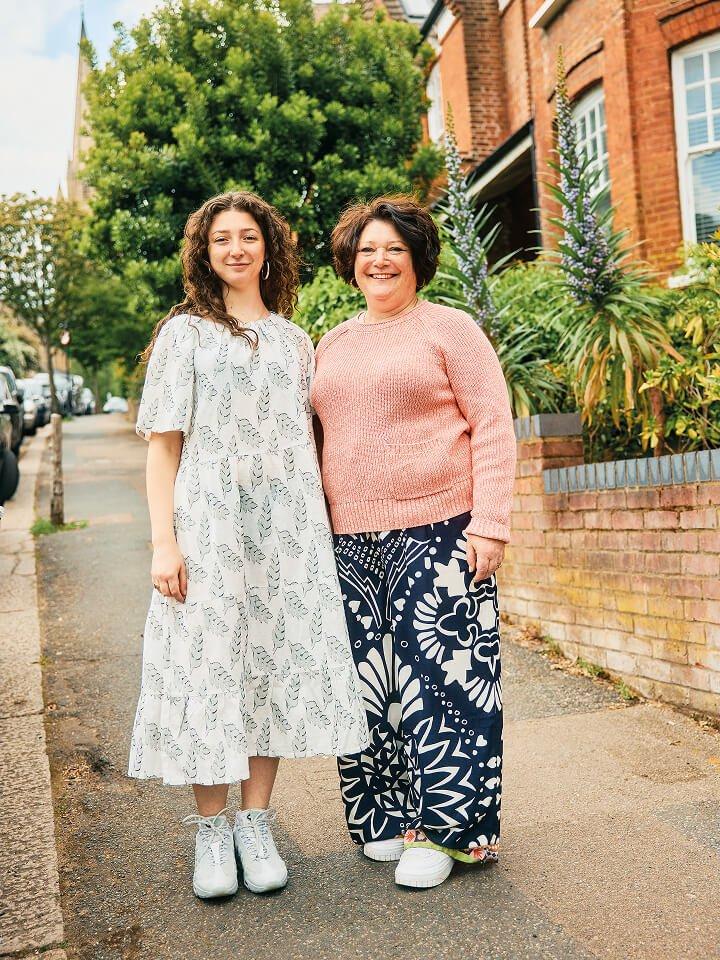 two women standing on a street in front of a house